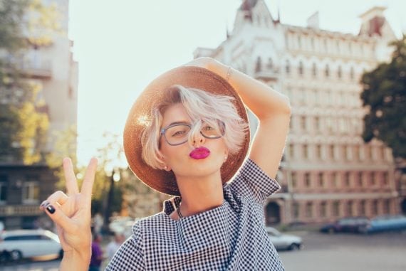 Closeup portrait of blonde girl with short hair having fun on the street on sunset background