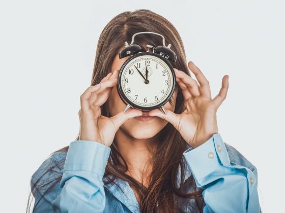 Woman with alarm clock covering her face