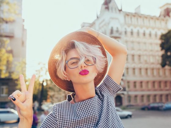 Closeup portrait of blonde girl with short hair having fun on the street on sunset background