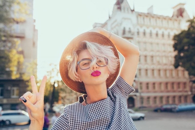 Closeup portrait of blonde girl with short hair having fun on the street on sunset background